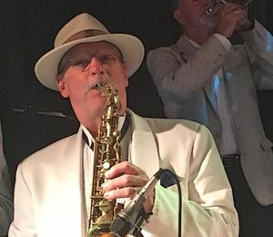 A picture of John Ovrebo playing the saxaphone on stage